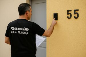 Imagem de oficial de justiça apertando a campainha para entregar intimação.